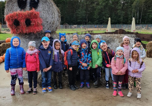 Grupa dzieci pozuje do wspólnego zdjęcia na tle słomianego posągu